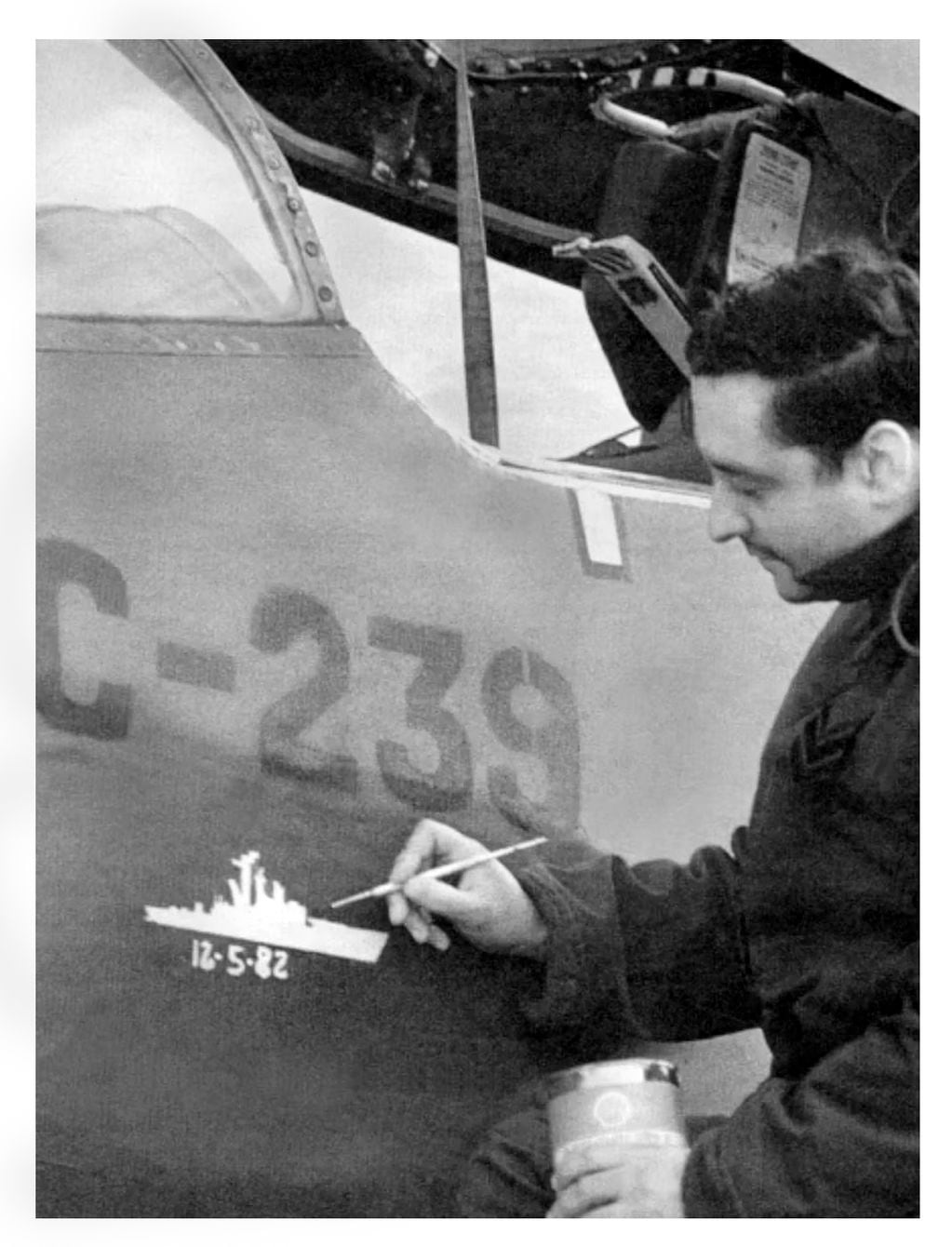 Foto tomada el 13 de mayo de 1982, se observa al suboficial Córdoba pintando la silueta del buque. Foto Fuerza Aérea Argentina

