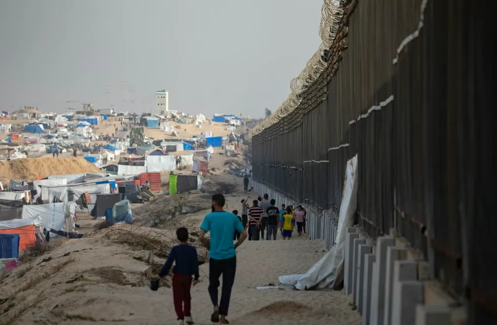 Civiles palestinos caminan junto al muro egipcio en Rafah, al sur de la Franja de Gaza.
