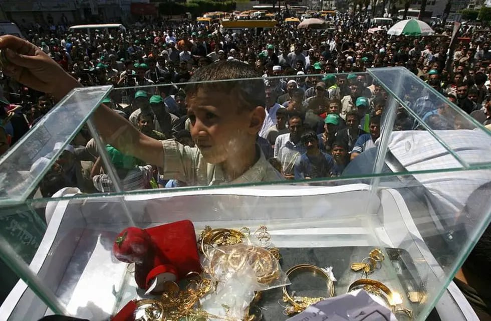 En la imagen, un niño gazatí ofreciendo una donación familiar al grupo terrorista durante una colecta en la Franja entre los civiles en 2006.