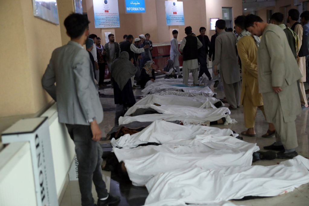 Hombres afganos intentan identificar los cadáveres en un hospital después de la explosión. (AP)