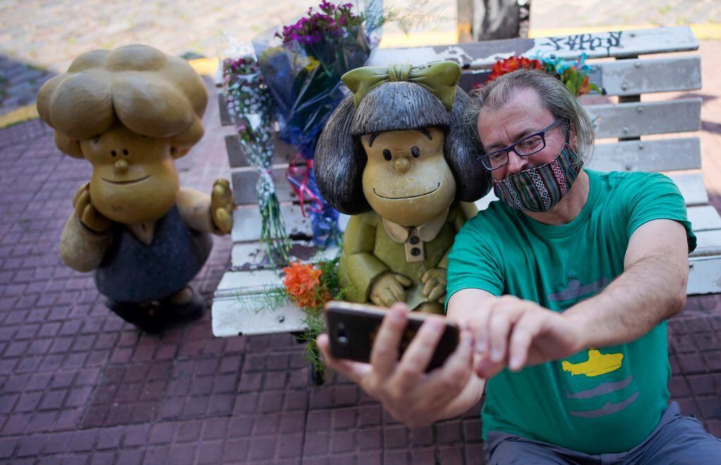 Un hombre se toma una selfie con una estatua del personaje de Mafalda en Buenos Aires, creado por Joaquín Salvador Lavado.