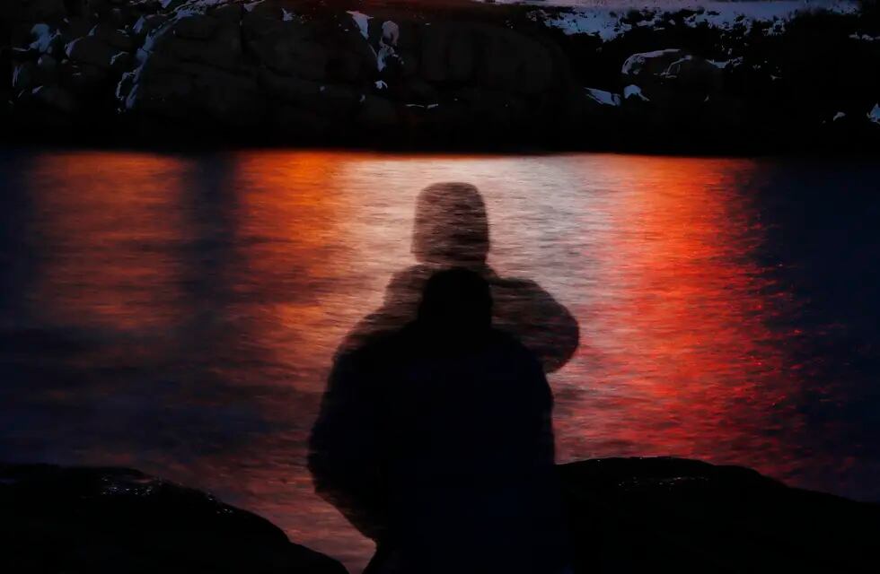 ARCHIVO - En esta fotografía de archivo, tomada con exposición prolongada, se ve la silueta de un hombre frente a luces reflejadas en las aguas de Cape Neddick, el 11 de diciembre de 2017, en Maine. (AP Foto/Robert F. Bukaty, archivo)