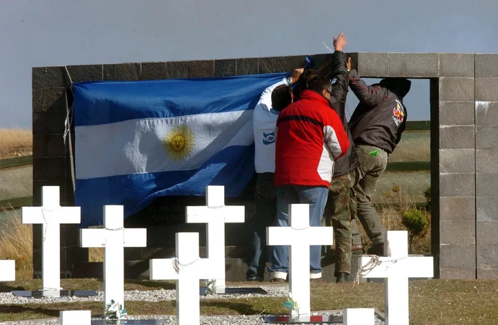 Excombatientes cuelgan la bandera argentina en el cementerio de Darwin. (Marcela Marbián/ Archivo La Voz)