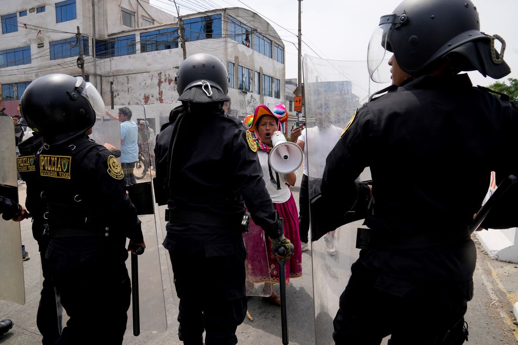 Una manifestante antigubernamental desafía a la policía que rodea la Universidad de San Marcos en Lima, Perú. (AP)