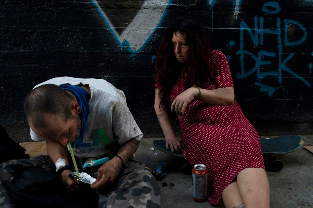 Jenn Bennett, que está drogada con fentanilo, se sienta sobre su patineta con un ojo morado mientras su amigo, Jesse Williams, fuma la droga el martes 9 de agosto de 2022, en Los Ángeles. (AP Foto/Jae C. Hong)