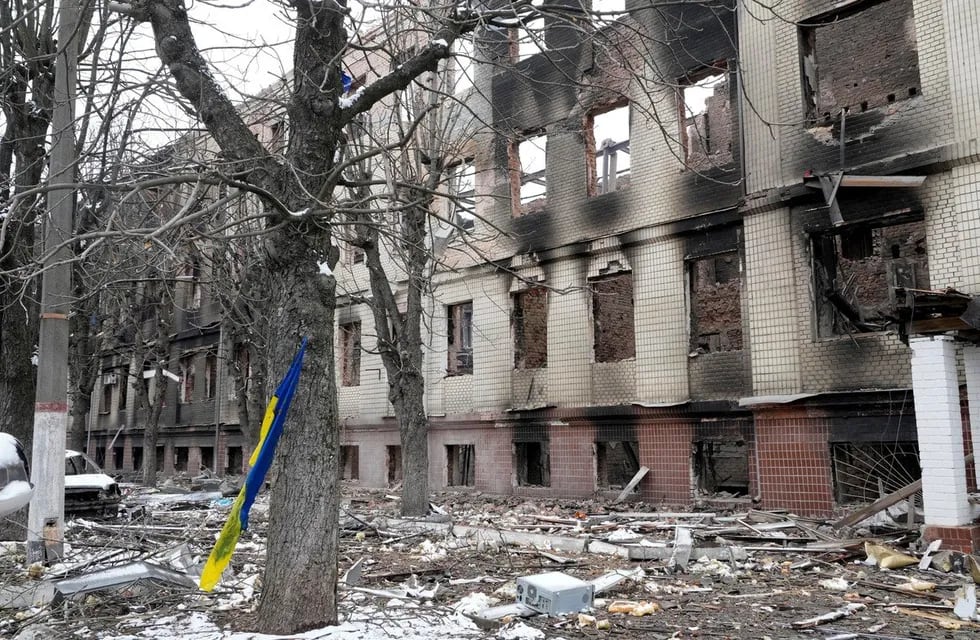 Una bandera nacional ucraniana se balancea en un árbol junto a un edificio de alojamiento destruido en Kiev. (AP)