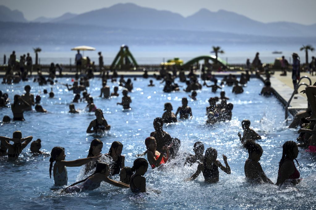 Personas tratando de evadir el calor en una piscina en Bellerive a orillas del Lago Ginebra, en Lausana, Suiza, el 23 de agosto de 2023.. (Laurent Gillieron/Keystone via AP)
