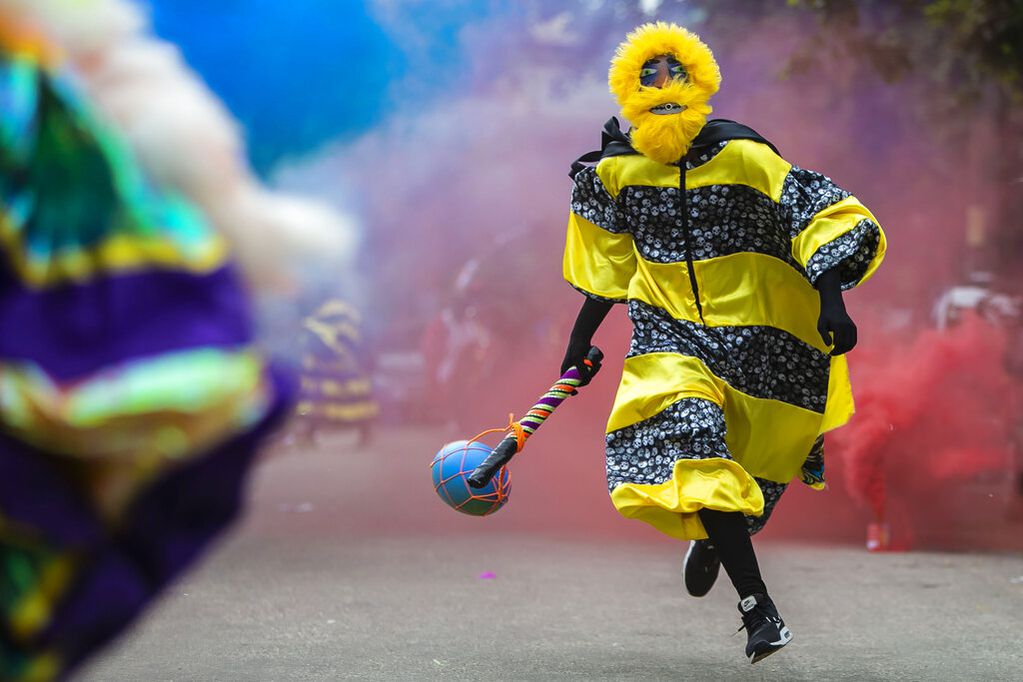 Un miembro de un grupo "bate-bola", hombres que se visten con exuberantes disfraces idénticos hechos a mano, llamados fantasías, corre por una calle durante una breve aparición en el Carnaval a pesar de las restricciones por el coronavirus, en Río de Janeiro
