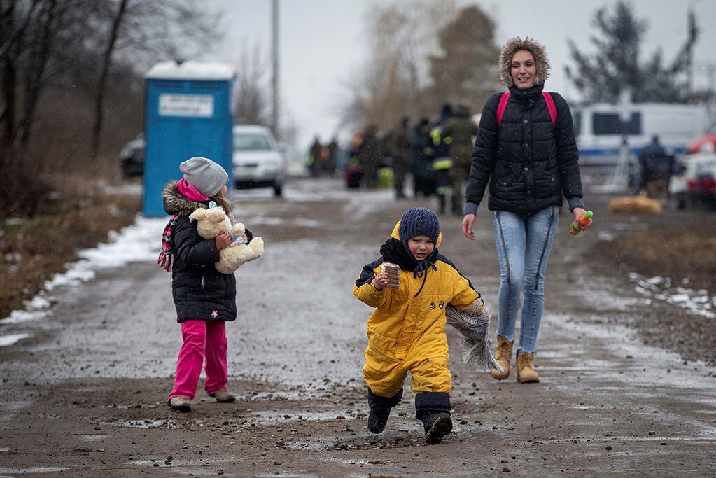 Niños, seguidos por una mujer, corren al llegar al cruce fronterizo en Medyka, Polonia, después de huir de Ucrania. (AP)