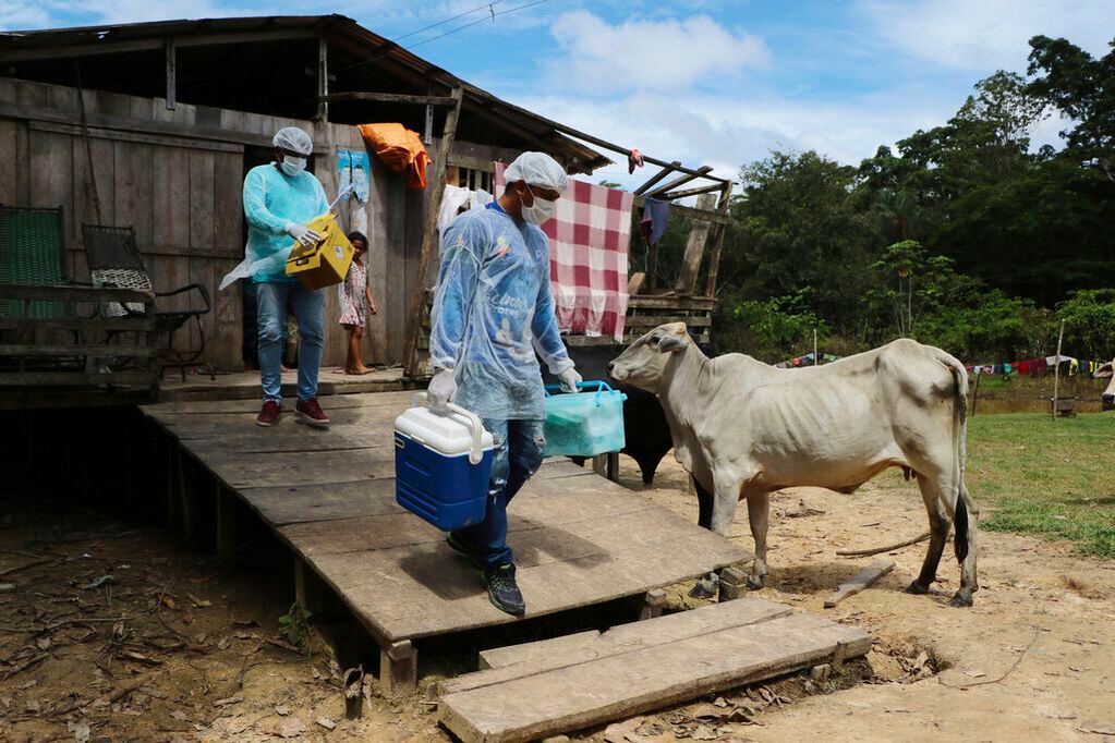 Los trabajadores médicos Diego Feitosa Ferreira, de 28 años (derecha), y Clemilton Lopes de Oliveira, de 41, salen de una vivienda donde una persona se negó a vacunarse contra el coronavirus, en la comunidad de Capacini, junto al río Purus, en la municipalía de Labrea, en el estado brasileño de Amazonas
