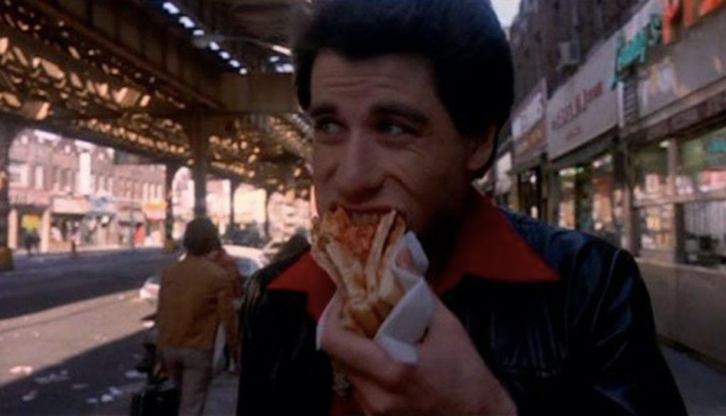 John Travolta se prepara para darlo todo en la pista con una pizza al paso. 