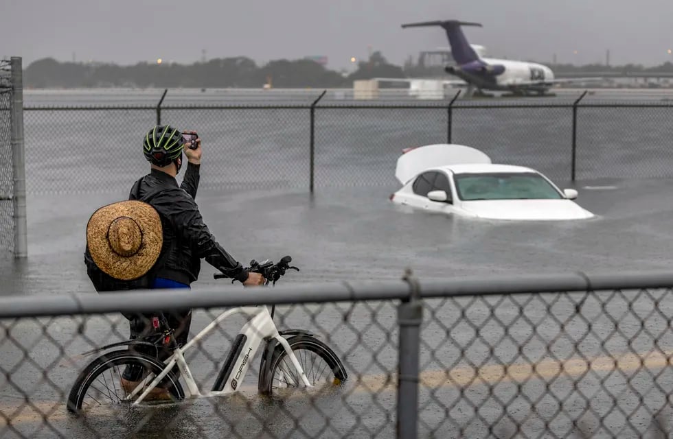 Una persona toma fotografías de un automóvil que está varado en el agua de la inundación en la carretera West Perimeter del Aeropuerto Internacional de Fort Lauderdale en Fort Lauderdale, Florida. Foto: EFE/EPA/CRISTOBAL HERRERA-ULASHKEVICH
