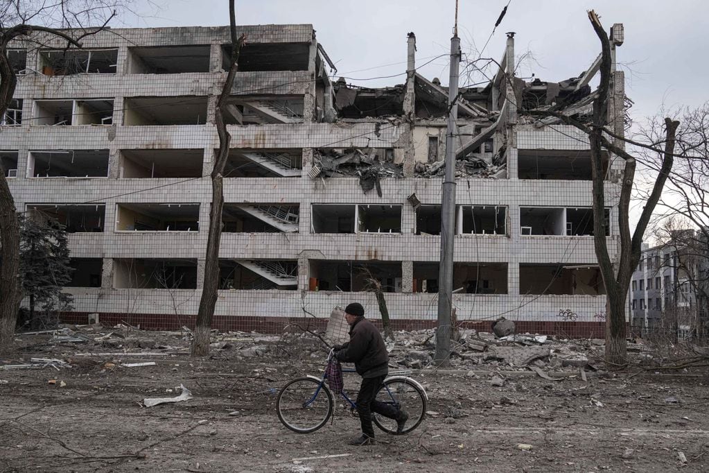 Un hombre anda en bicicleta frente a edificios destrozados, un esqueleto de lo que fue. (AP Photo/Evgeniy Maloletka)