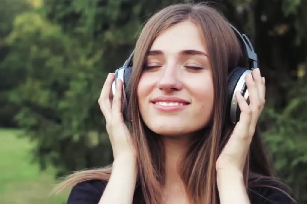 chica escuchando música con auriculares en un jardín