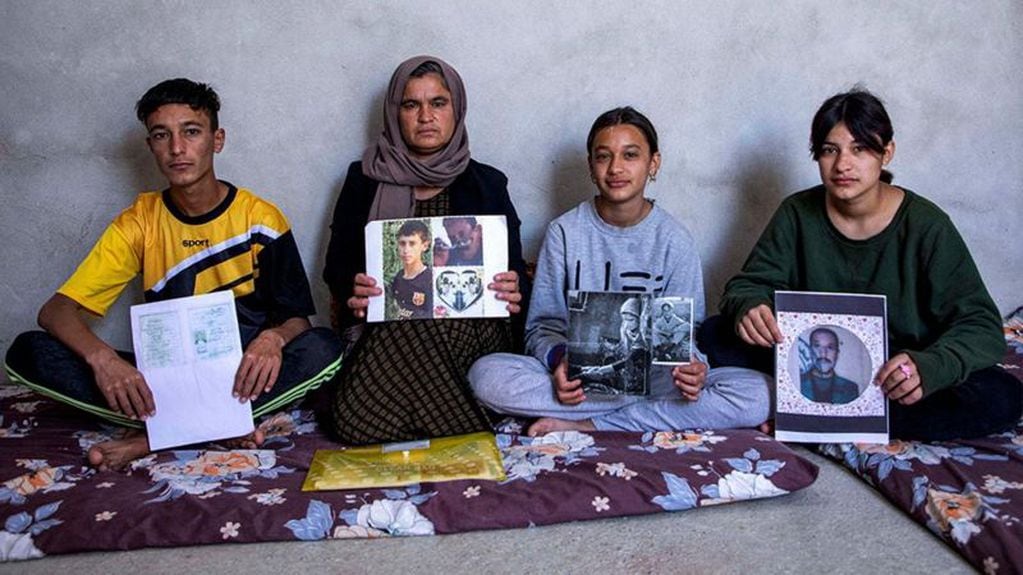 Bahar y sus tres hijos sostienen fotos de sus familiares desaparecidos. Foto: BBC News