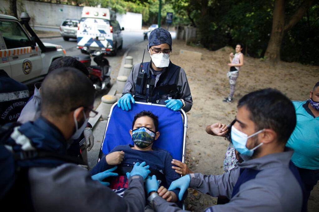 Con mascarillas como medida de precaución contra el coronavirus, paramédicos voluntarios del grupo Ángeles de las Vías trasladan a un niño en camilla a su ambulancia luego de un accidente de moto, en Caracas, Venezuela