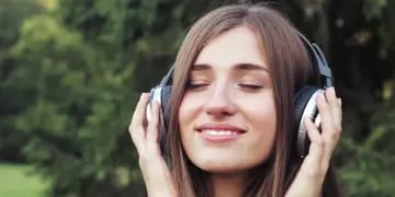 chica escuchando música con auriculares en un jardín