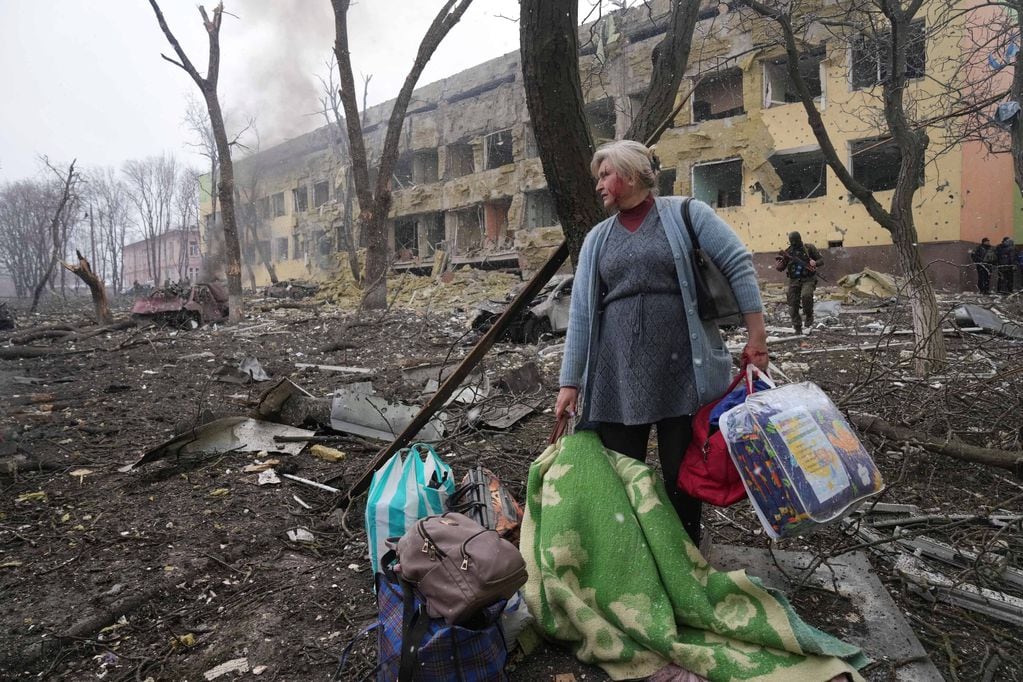 Una mujer con sus pertenencias frente al hospital bombardeado en Mariúpol. (AP Photo / Evgeniy Maloletka)