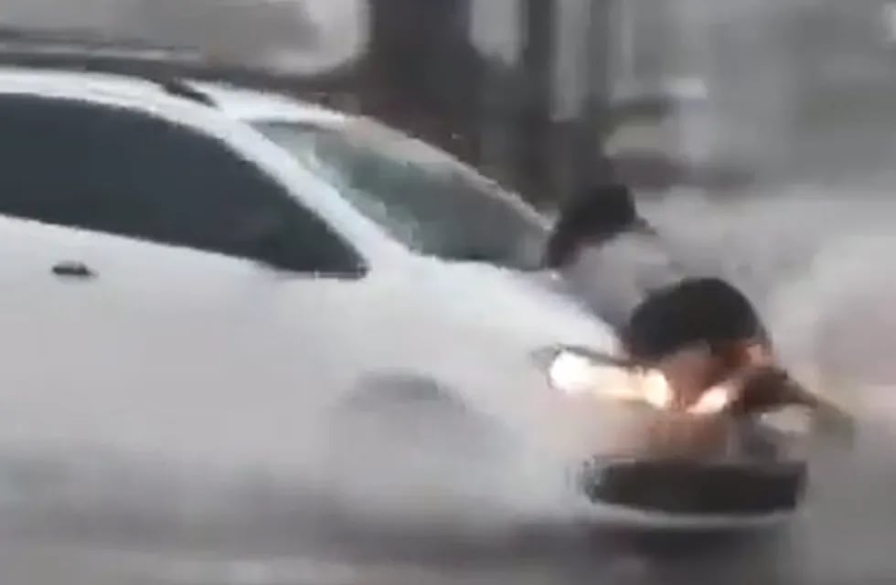 La mujer quiso evitar que el hombre hiciera oleaje en la calle inundada - Captura de video