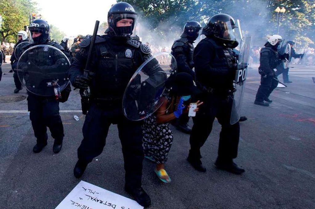 
AFP | Una manifestante intenta pasar entre la línea policial mientras empujan a los manifestantes fuera de la Casa Blanca.
   