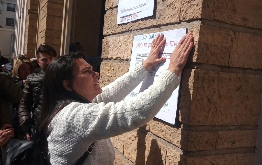 Carina Sedano pega un cartel con bonos de sueldo en la Casa de Gobierno.