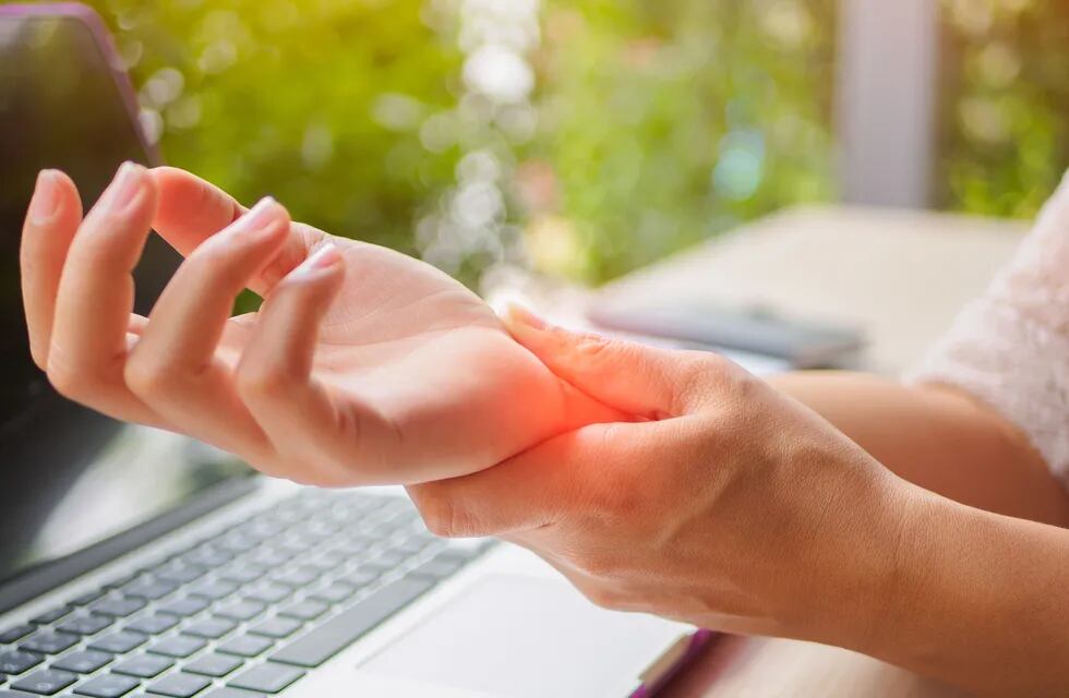 Closeup woman holding her painful hand from using computer. Office syndrome hand pain by occupational disease.