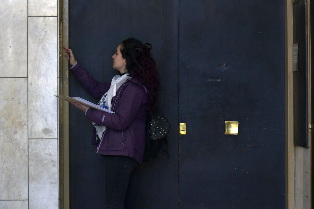 Mariela López toca los timbres en un edificio de la ciudad de Mendoza. Foto: Orlando Pelichotti / Los Andes