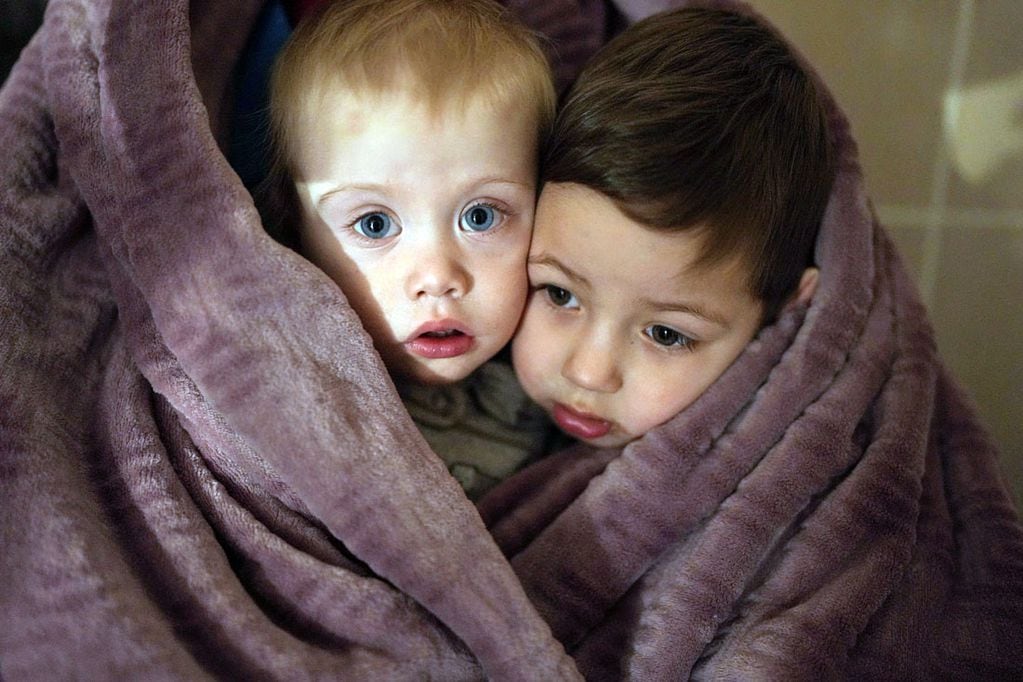Los hijos de los trabajadores médicos se calientan con una manta mientras esperan a sus familiares en un hospital de Mariupol. (AP /Evgeniy Maloletka)