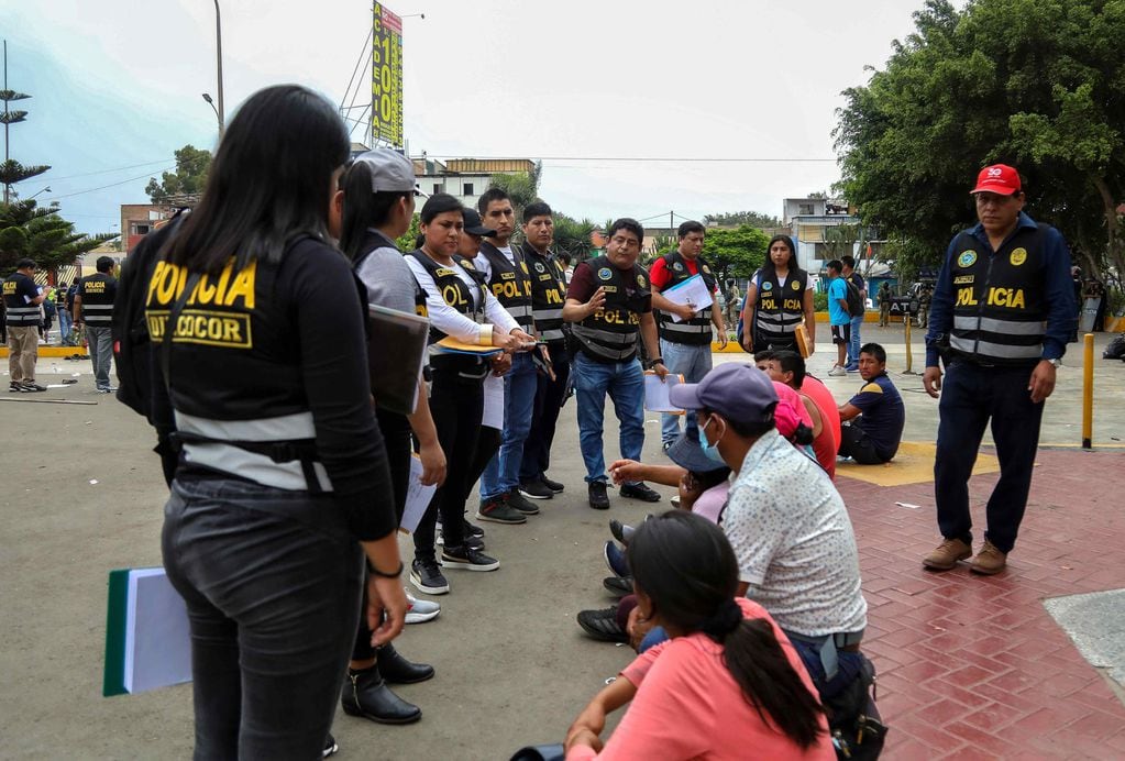 Integrantes de la Policía Nacional de Perú (PNP) vigilan a un grupo de personas detenidas en el campus de la Universidad Nacional Mayor de San Marcos (UNMSM) hoy, en Lima (Perú). Foto: EFE/Connie Calderón