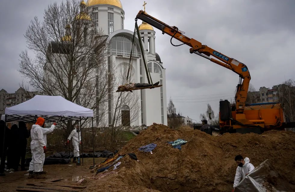 Una grúa levanta un cadáver de una fosa común con el fin de que sea trasladado a una morgue para su identificación, en Bucha, a las afueras de Kiev, Ucrania. / Foto: AP