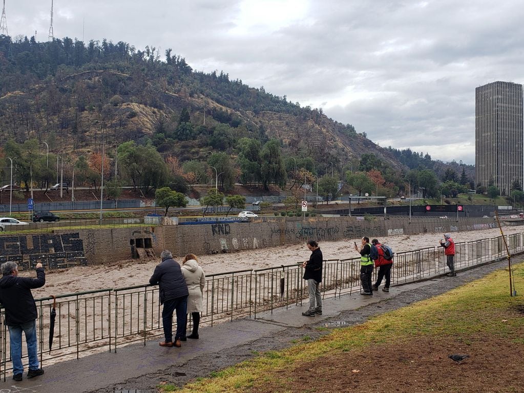 CH0. SANTIAGO (CHILE), 23/06/2023.- Personas observan hoy el elevado caudal del río Mapocho, producto de las intensas lluvias en Santiago (Chile). EFE/ Javier Martín
