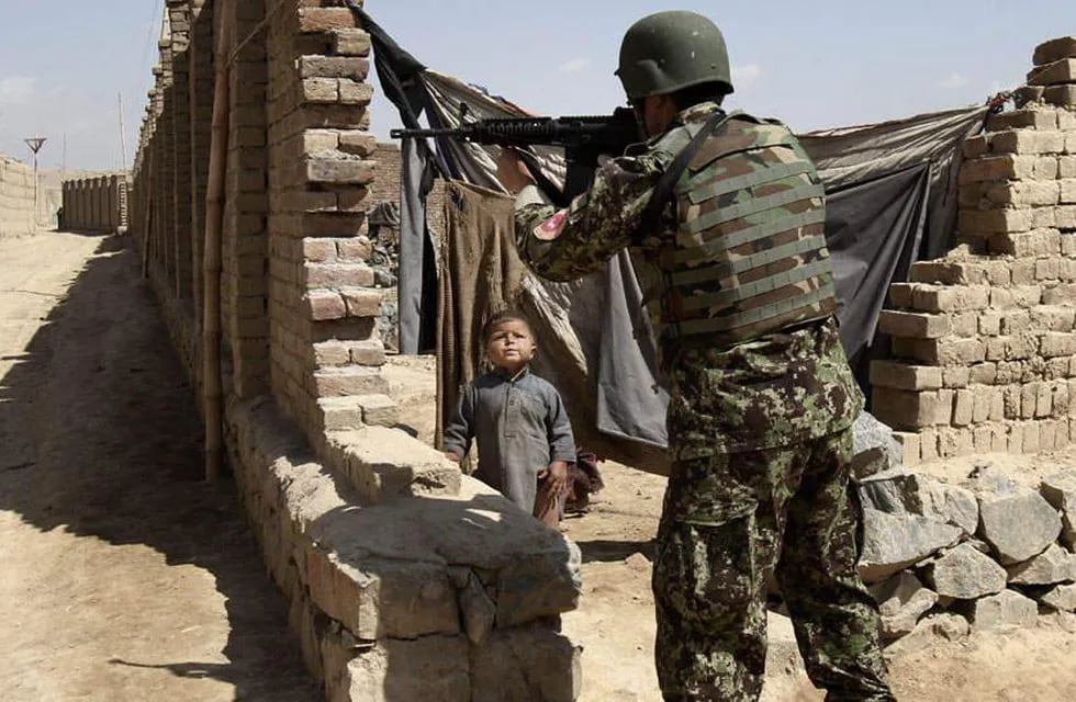 Demasiada guerra. Un soldado afgano apunta con su arma en las afueras de Kabul; el niño es testigo (AP).