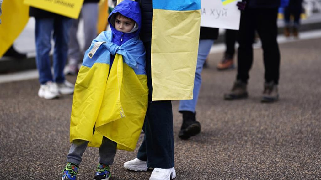 Un niño ucraniano refugiado junto a su padre en una manifestación. Foto: EFE