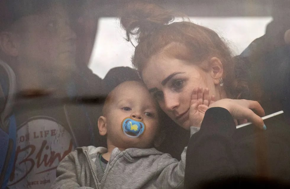 Una mujer sostiene a su bebé dentro de un colectivo cuando huyen de Kiev, Ucrania (AP)