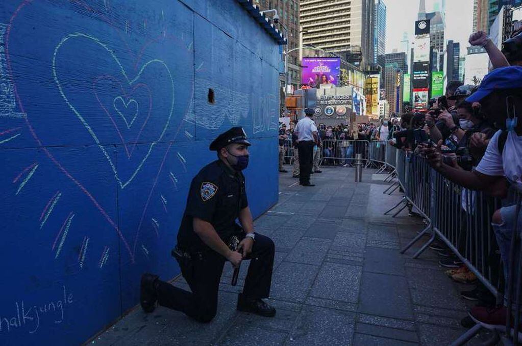 
AFP | Un oficial de policía de la ciudad de Nueva York se arrodilla durante una manifestación de los manifestantes en Times Square.
   