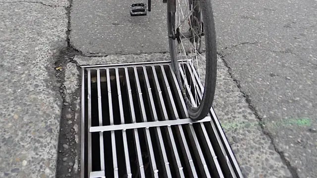 rueda de bicicleta encajada en una alcantarilla