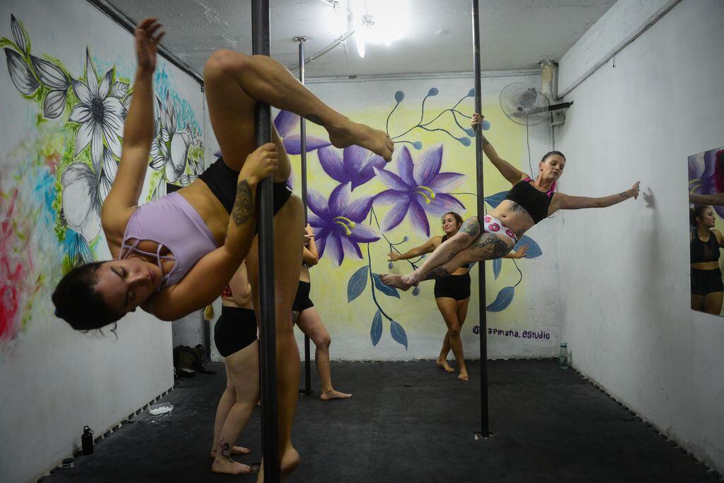 Mujeres y hombres practican Pole Dance, una disciplina que combina arte y deporte que exige un gran esfuerzo y despliegue físico para lograr las formas estéticas en la barra.