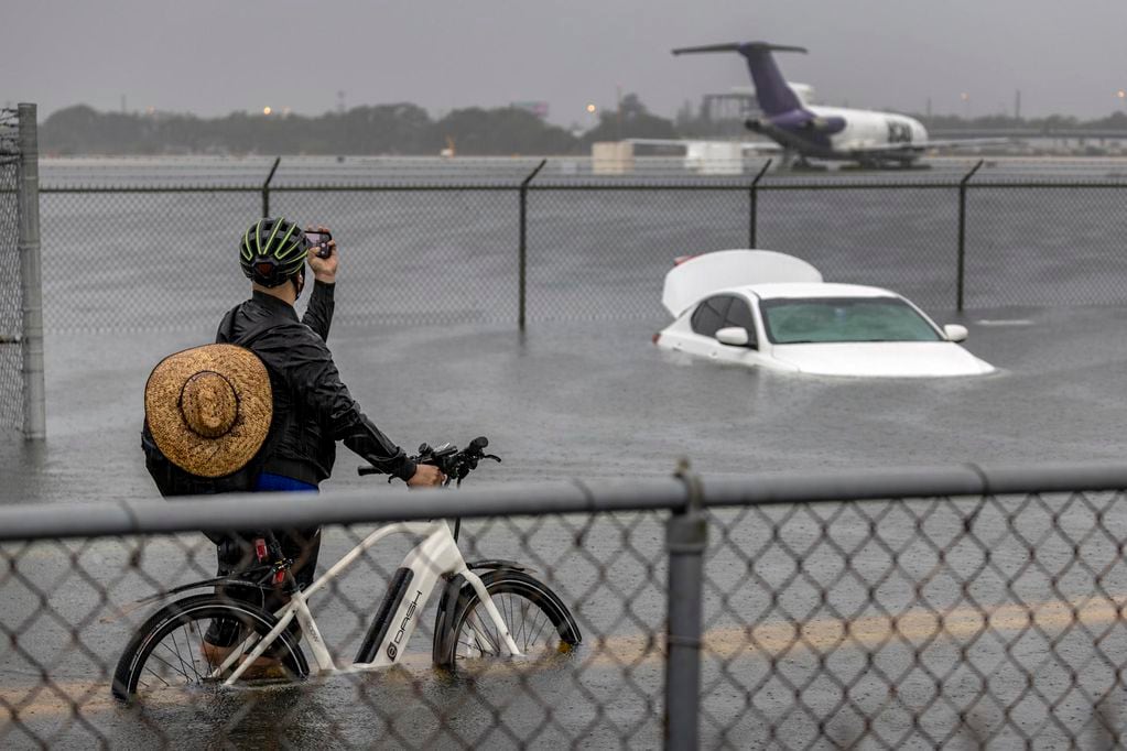 Una persona toma fotografías de un automóvil que está varado en el agua de la inundación en la carretera West Perimeter del Aeropuerto Internacional de Fort Lauderdale en Fort Lauderdale, Florida. Foto: EFE/EPA/CRISTOBAL HERRERA-ULASHKEVICH