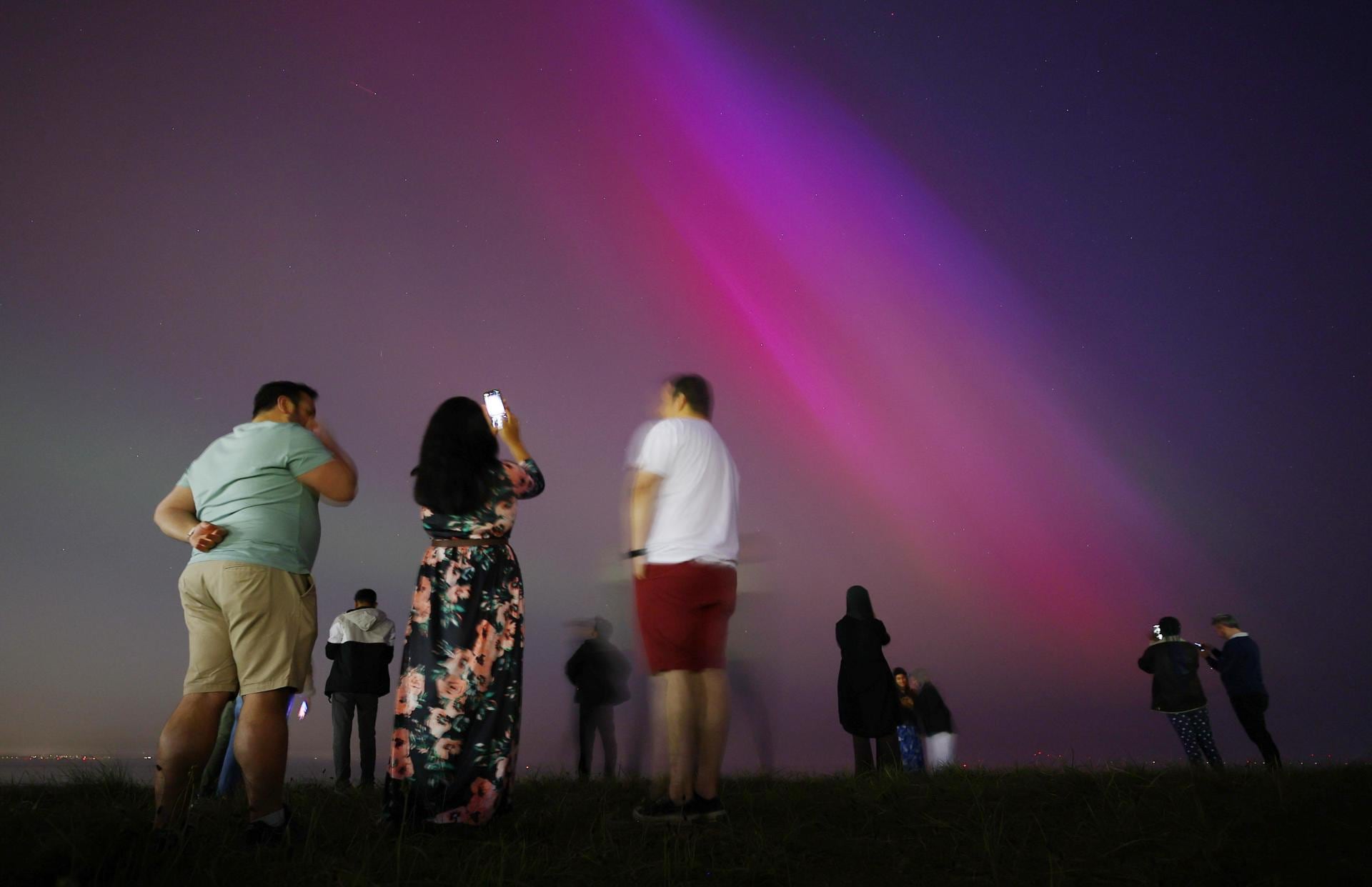 Un grupo de personas se reúne en Crosby Beach para contemplar la Aurora Boreal, en Gran Bretaña. Foto: EFE