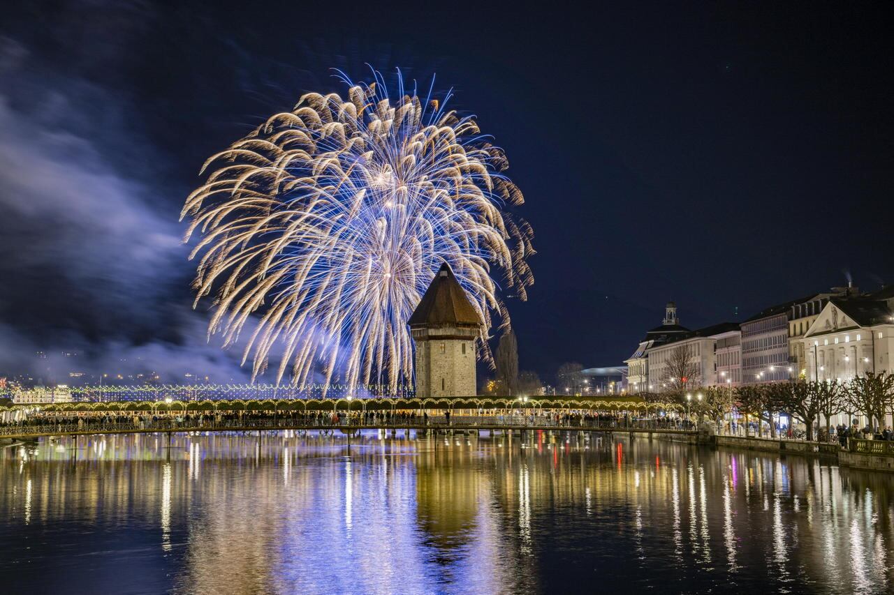 Los fuegos artificiales de Año Nuevo estallan sobre el famoso Puente de la Capilla y el Casco Antiguo en Lucerna, Suiza, el 01 de enero de 2024. EFE/EPA/URS FLUEELER