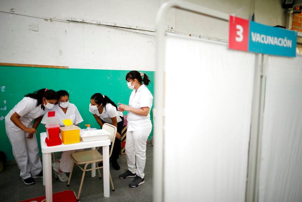 Enfermeras leen las instrucciones para inyectar las vacunas Sputnik V contra el COVID-19 en la escuela pública Bernal, a las afueras de Buenos Aires, Argentina