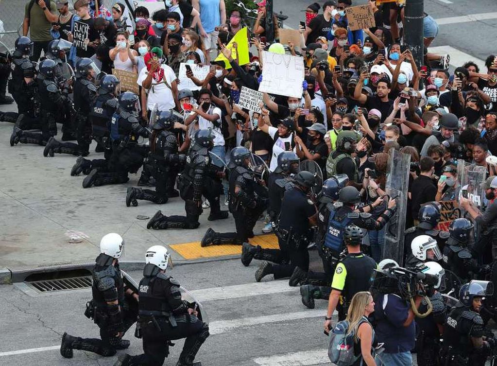 
AP | En una muestra de paz y solidaridad, los policías con escudos antidisturbios se arrodillaron frente a los manifestantes.
   