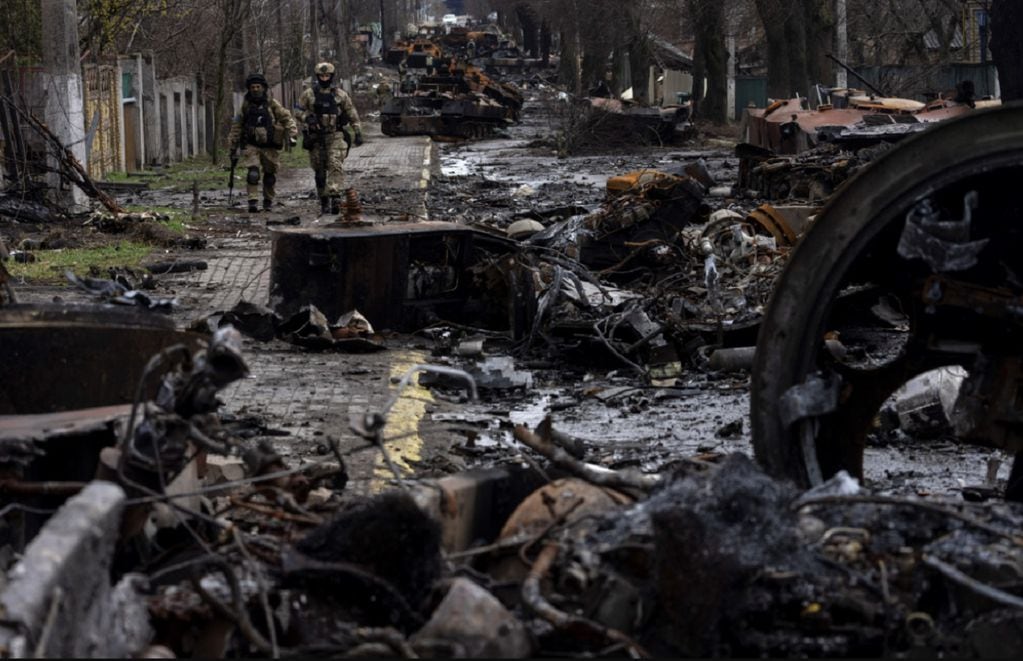 Soldados caminan entre tanques rusos destruidos en Bucha, en las afueras de Kiev, Ucrania, el domingo 3 de abril de 2022. (AP)