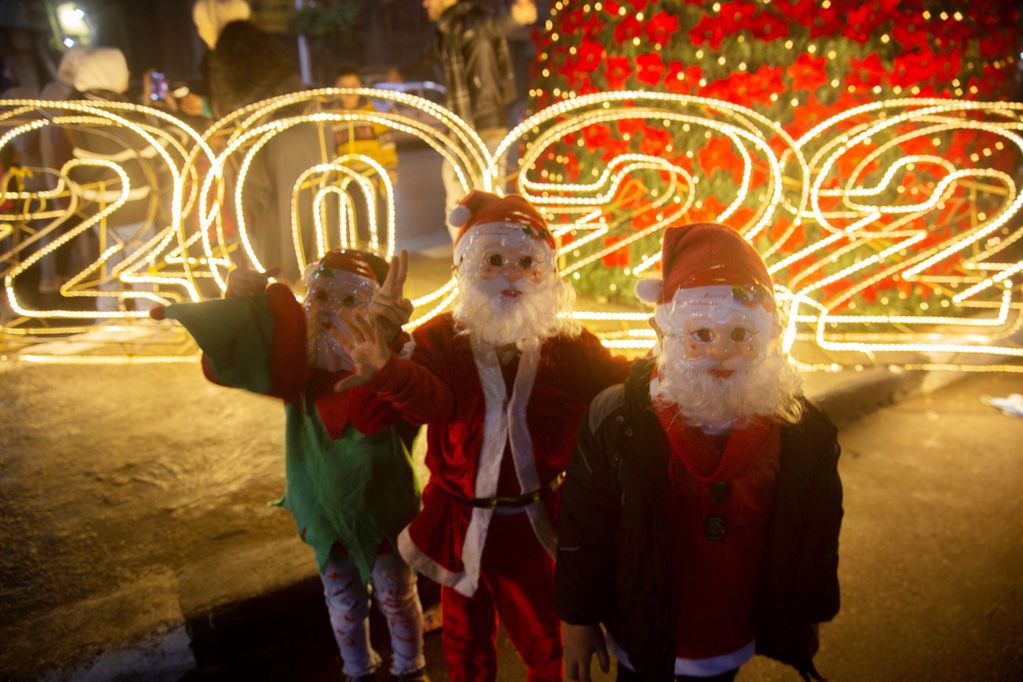 Los niños usan máscaras de Santa Claus mientras posan frente a las decoraciones navideñas y el formulario 2022 mientras celebran el año nuevo en El Cairo, Egipto