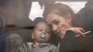 Una mujer sostiene a su bebé dentro de un colectivo cuando huyen de Kiev, Ucrania